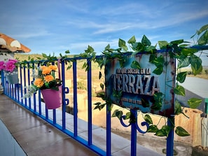 A blue metal railing with potted plants and a sign with text.