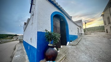 A building with a blue and white facade, a large arched entrance, and a potted plant with stones.