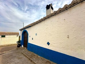 A building with a white and blue facade, a tiled roof, and a single visible door.