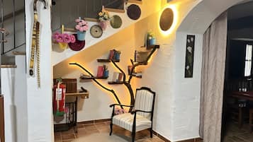A staircase with a unique tree-like shelf design, a chair, and a fire extinguisher.