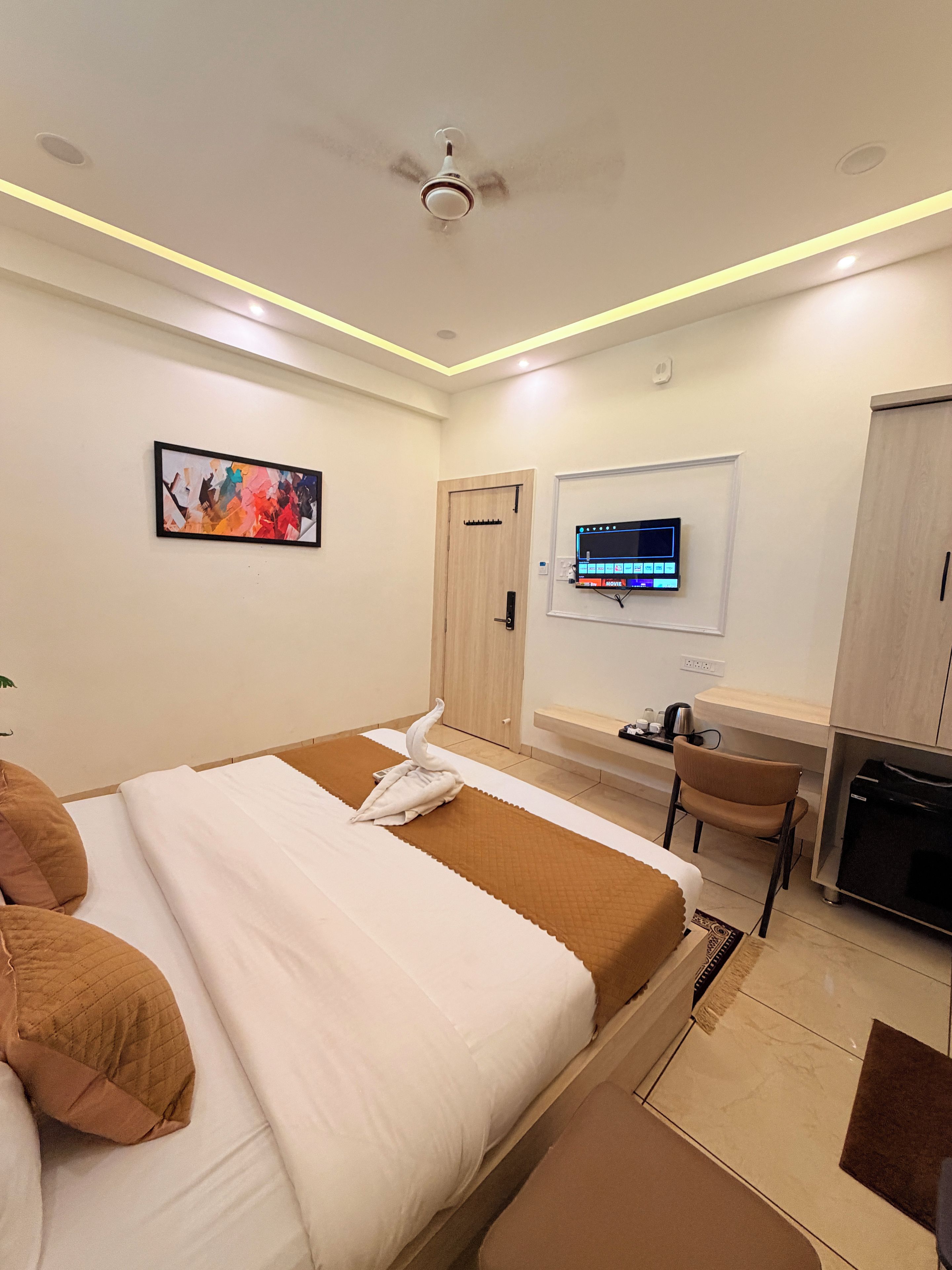 A hotel room with a bed, a desk, a chair, a television, and a door.