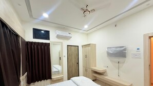 Habitación de hotel con cama, televisor, aire acondicionado, armario y espejo de baño.