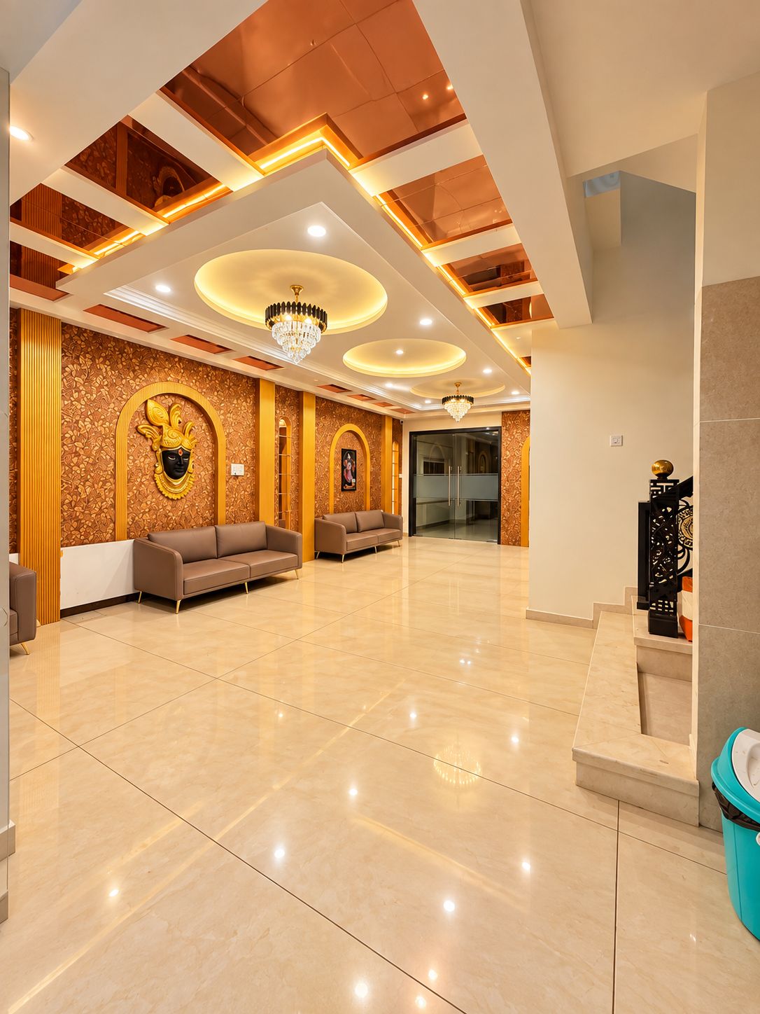 A spacious lobby with a high ceiling, chandeliers, and a patterned wall.