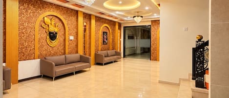 Un vestíbulo amplio con techo alto, candelabros y un revestimiento de pared con diseño.