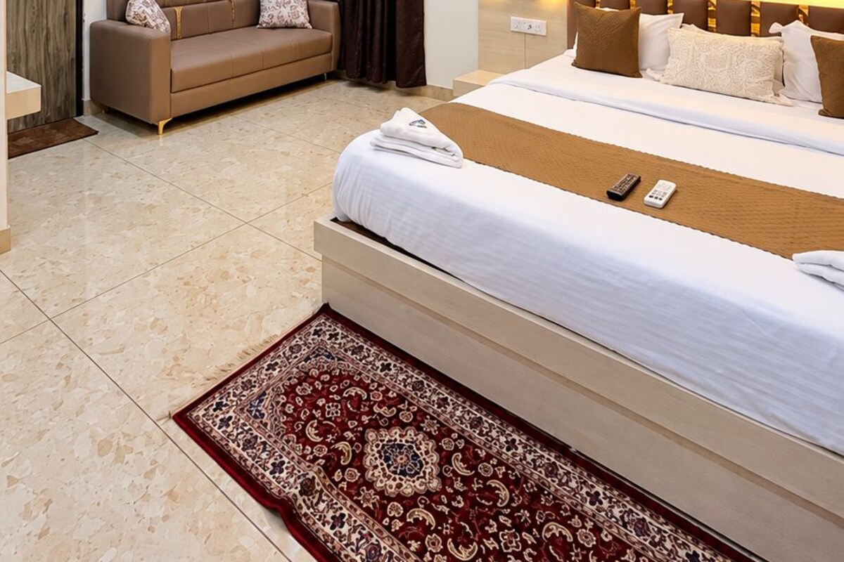 Una habitación de hotel con una cama, un sofá, una alfombra y un ventilador de techo.