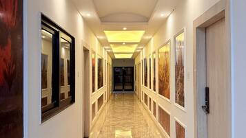 A long, narrow hallway with a polished floor, framed artwork on the walls, and recessed lighting.