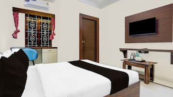 Habitación de hotel con cama, escritorio, silla, televisor montado en la pared y aire acondicionado.