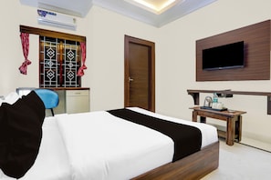 A hotel room with a bed, a desk, a chair, a TV mounted on the wall, and an air conditioning unit. - Townhouse Madiwala Lake Park (Bengaluru)