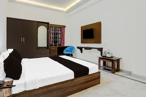 A hotel room with a bed, a desk with a chair, a wardrobe, a mirror, and a television on the wall. - Townhouse Madiwala Lake Park (Bengaluru)