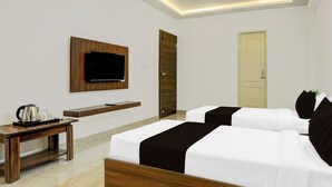 Ein Hotelzimmer mit zwei Betten, einem an der Wand montierten Fernseher, einem Couchtisch und einer Tür.