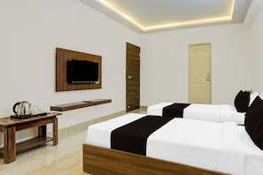 A hotel room with two beds, a TV mounted on the wall, a coffee table, and a door. - Townhouse Madiwala Lake Park (Bengaluru)