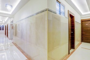 A hotel corridor with a marble floor, a wooden door, and a chandelier.