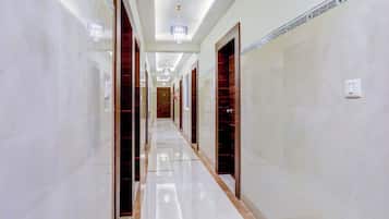 A corridor with marble flooring, wooden doors, and a chandelier.