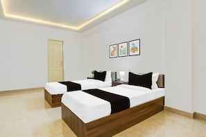 A hotel room with two beds, a door, and three framed artworks on the wall. - Townhouse Madiwala Lake Park (Bengaluru)