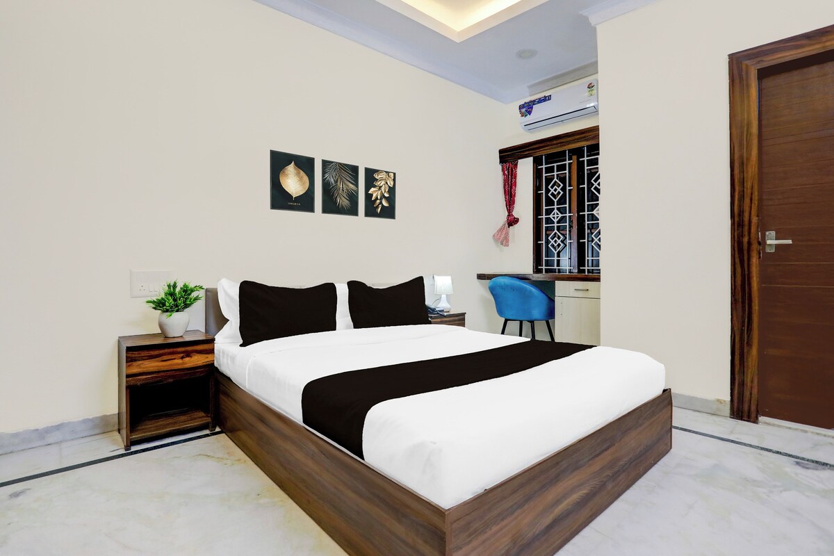 A neatly arranged bedroom with a bed, bedside table, and a small desk area.