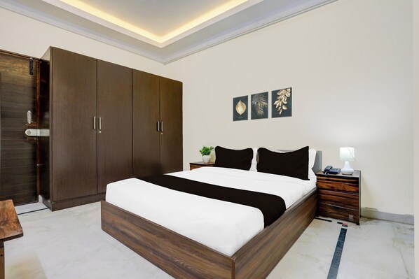 A bedroom with a large bed, a wardrobe, a bedside table with a lamp, and three framed artworks on the wall. - Townhouse Madiwala Lake Park (Bengaluru)