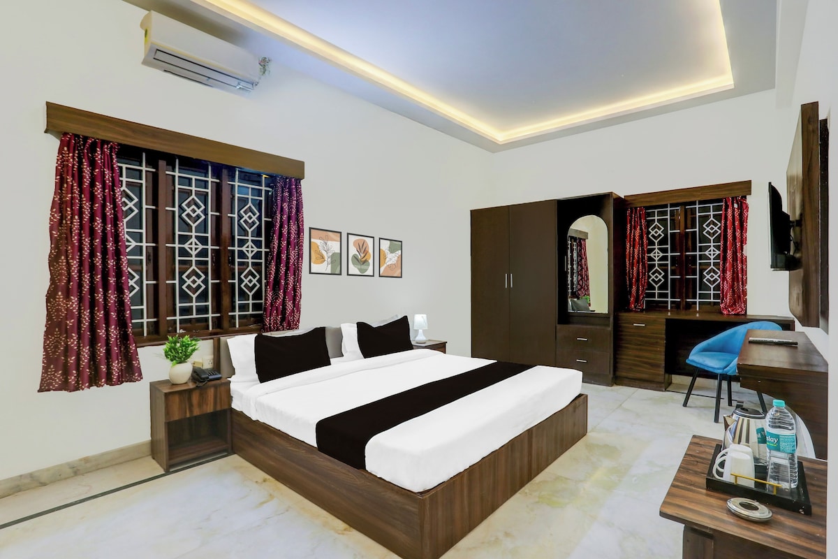 A hotel room with a bed, a desk, a wardrobe, and a television.