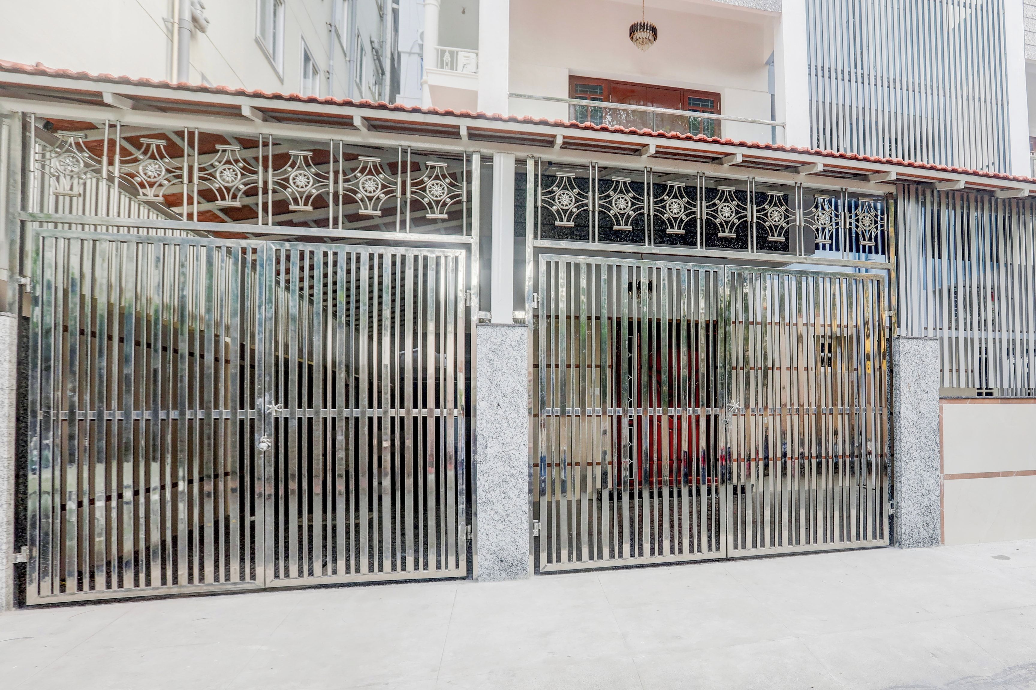 Una entrada protegida por un portón de metal y un balcón con barandillas decorativas.