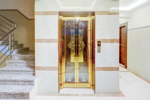 An elevator with a glass door and a decorative golden frame. - Townhouse Madiwala Lake Park (Bengaluru)