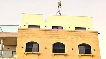 Um edifício de vários andares com telhado plano e antena de satélite no topo.
