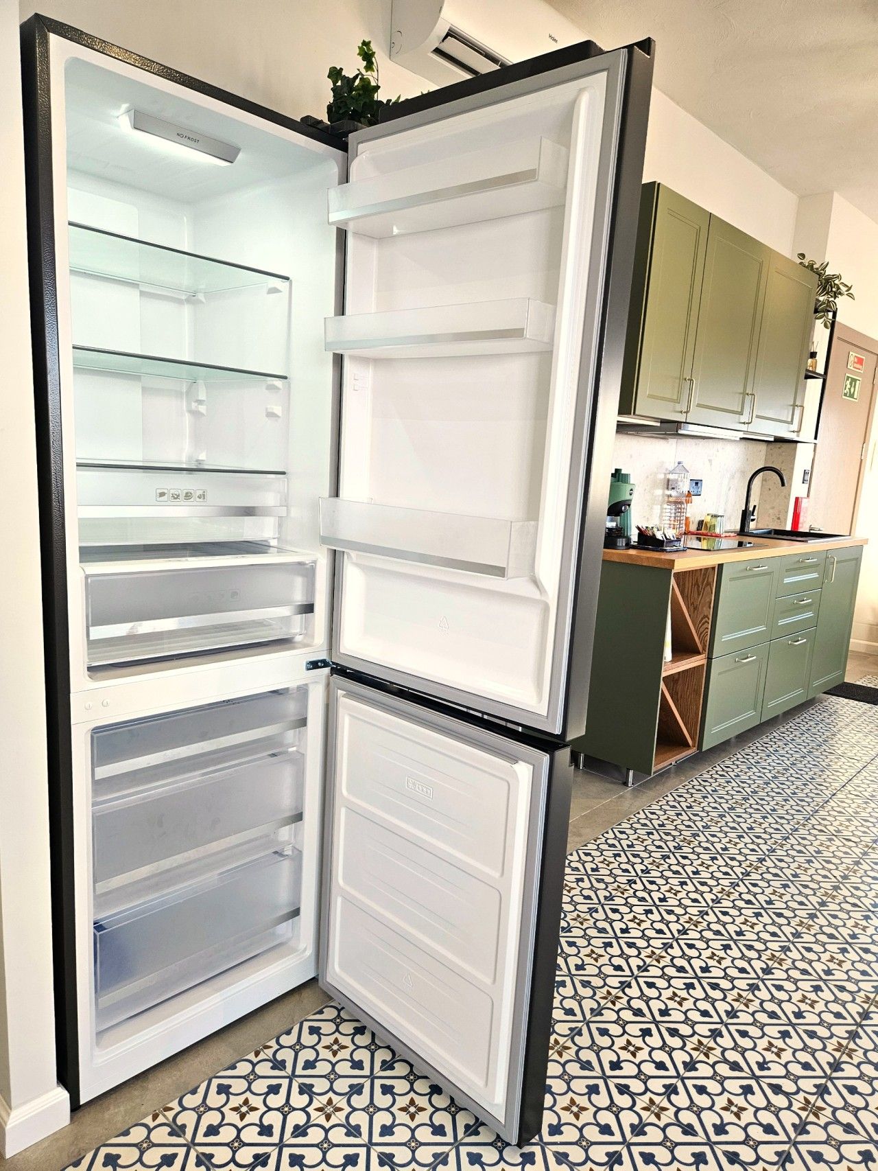 Una cucina con un frigorifero a doppia porta, un lavello e un pavimento decorato.