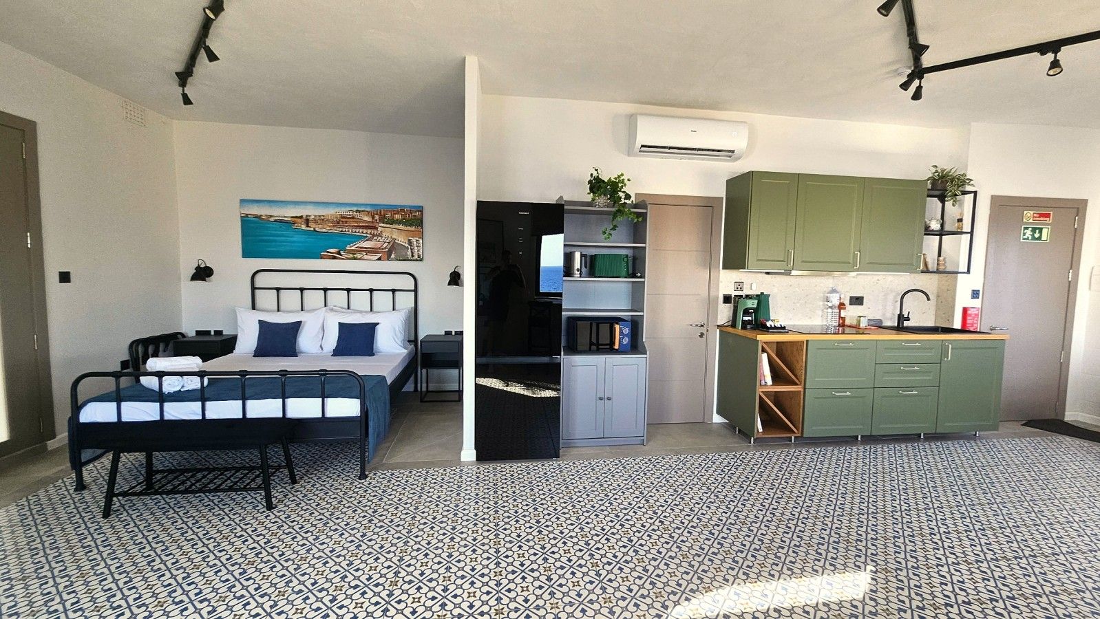 A compact room with a bed, a kitchenette, and a bathroom.