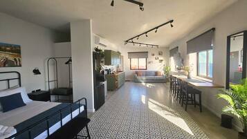Um espaço compacto com cama, cozinha compacta, área de refeições e sofá.