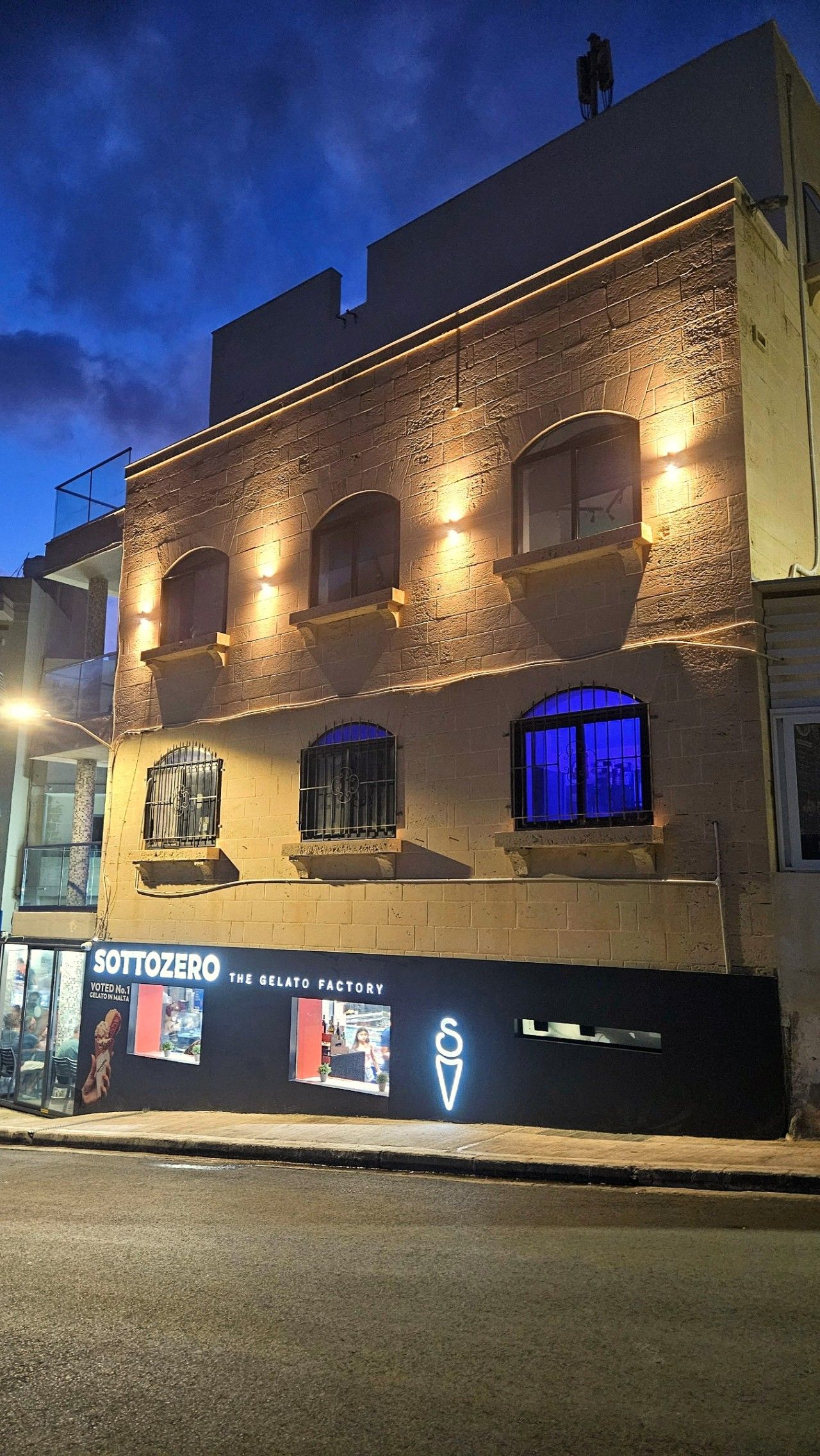 Um edifício com uma placa indicando 'SottoZero The Gelato Factory' à noite.