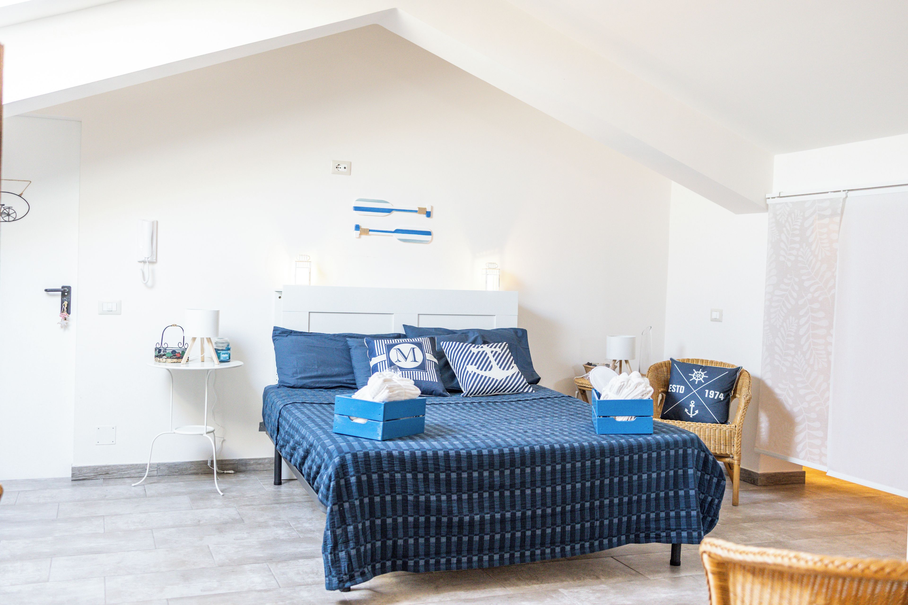 Ein Schlafzimmer mit Bett, Stuhl, kleinem Tisch und Wandleuchte.