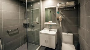 Et stilfuldt badeværelse med brusekabine i glas, en hvid vask og et toilet.