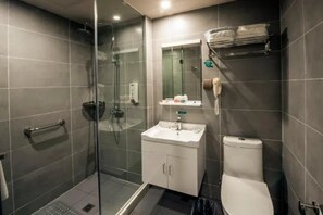 Un baño moderno con cabina de ducha de vidrio, un lavabo blanco y un inodoro.