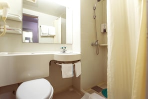 Un baño con inodoro, lavamanos, espejo, ducha y toallero.