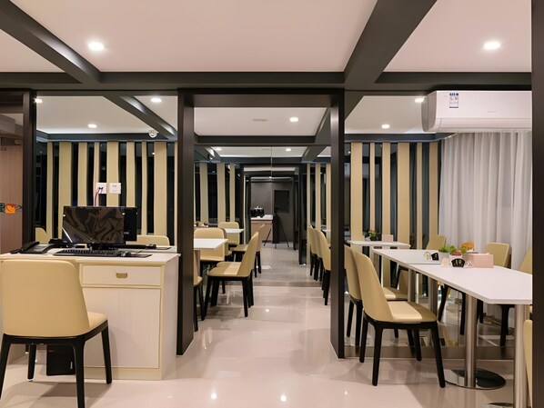 Un moderno vestíbulo de hotel con una recepción, una zona de estar y un largo pasillo que conduce al comedor.