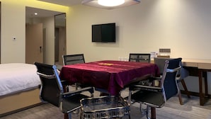 Habitación de hotel con cama, una mesa con sillas, televisor de pantalla plana y aire acondicionado instalado en el techo.
