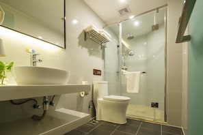 Un baño moderno con ducha envuelta en vidrio, un lavabo blanco y un inodoro.