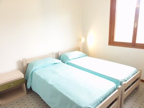 A single room with two beds, a nightstand, a wall-mounted light, and a window. - First-floor Accommodation in Residence With Pool (San Michele al Tagliamento)