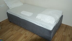 A single bed with white bedding, a grey headboard, and a white pillow. - Hotel Shree Banaras (Varanasi)