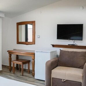 A room with a wooden desk, a television, a sofa, and a mirror. - Astroia Pansiyon (Lapseki)