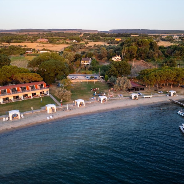 A coastal hotel with a beach, a parking area, and a view of the surrounding landscape. - Astroia Pansiyon (Lapseki)