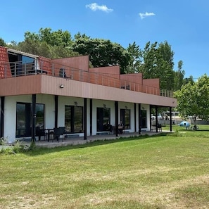 A modern building with a flat roof, large windows, and a covered outdoor area with seating. - Astroia Pansiyon (Lapseki)