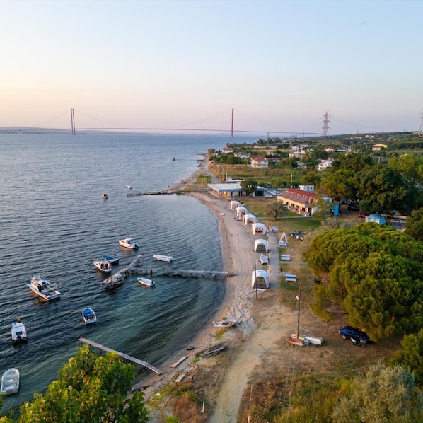 A coastal area with a beach, boats, and a bridge in the background. - Astroia Pansiyon (Lapseki)