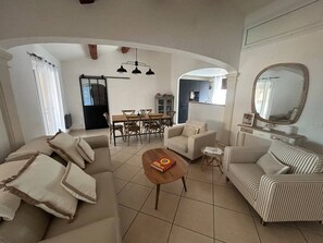 A living room with a sofa, armchairs, a coffee table, and a dining area with chairs and a table. - Cozy 2-bedroom apartment, with a terrace, 10 meters from Nartelle Beach (Sainte-Maxime)