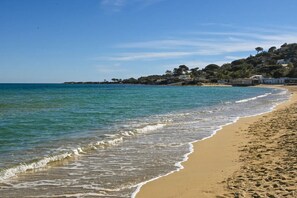 A beach with clear blue water, sandy shore, and buildings in the background. - Cozy 2-bedroom apartment, with a terrace, 10 meters from Nartelle Beach (Sainte-Maxime)