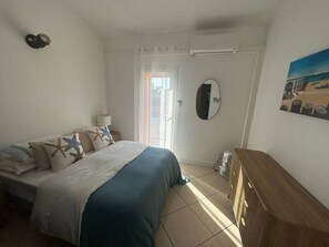 Een slaapkamer met een bed, een dressoir, een spiegel en een schilderij aan de muur.