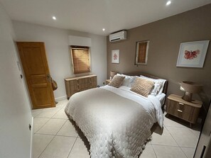 Ein Schlafzimmer mit Bett, Nachttischen, einem Kleiderschrank und einem Fenster mit Jalousien.