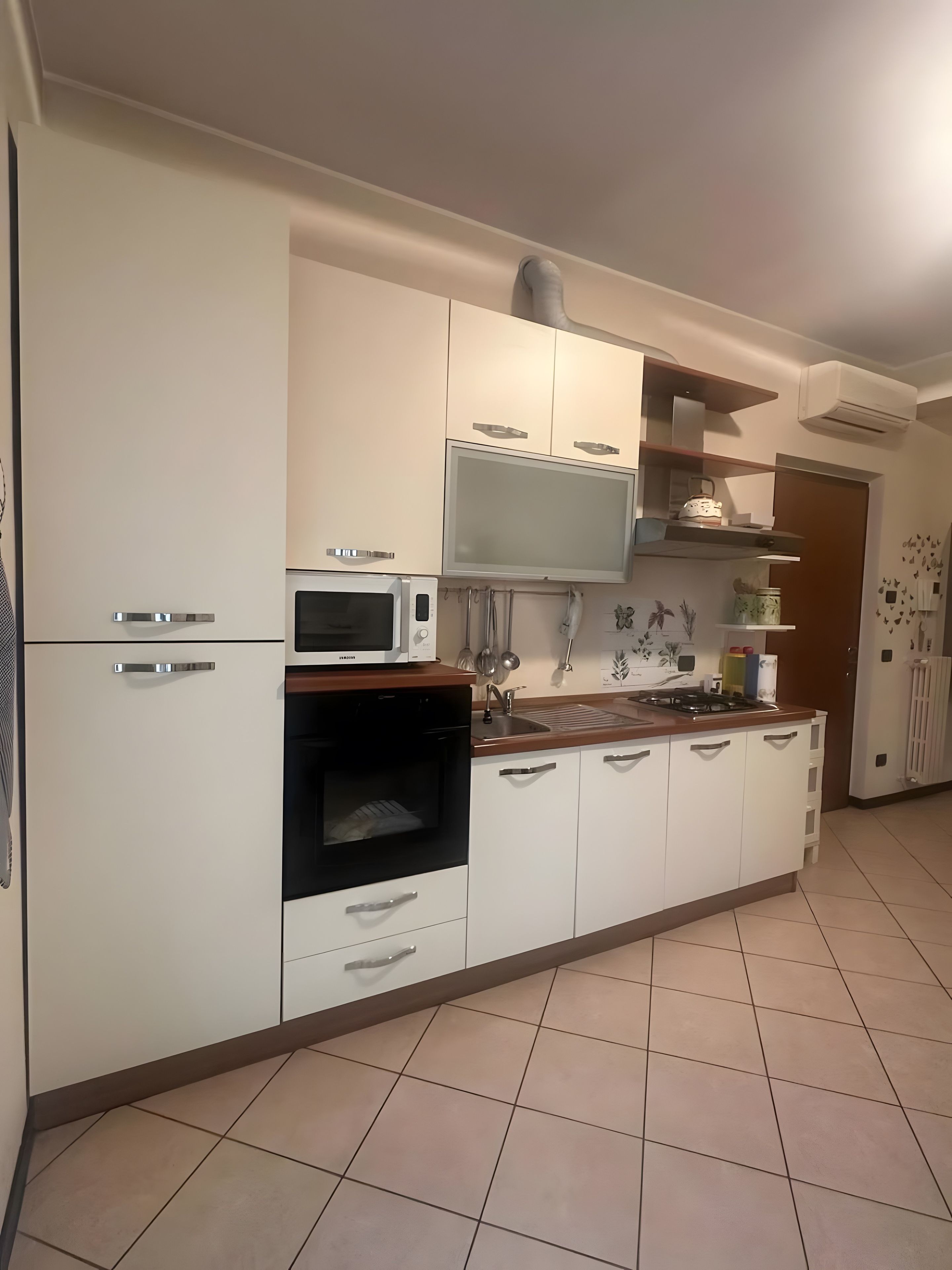 Een moderne keuken met witte kasten, een magnetron, een oven en een gasfornuis.