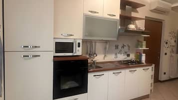 Een moderne keuken met witte kasten, een magnetron, een oven en een gasfornuis.