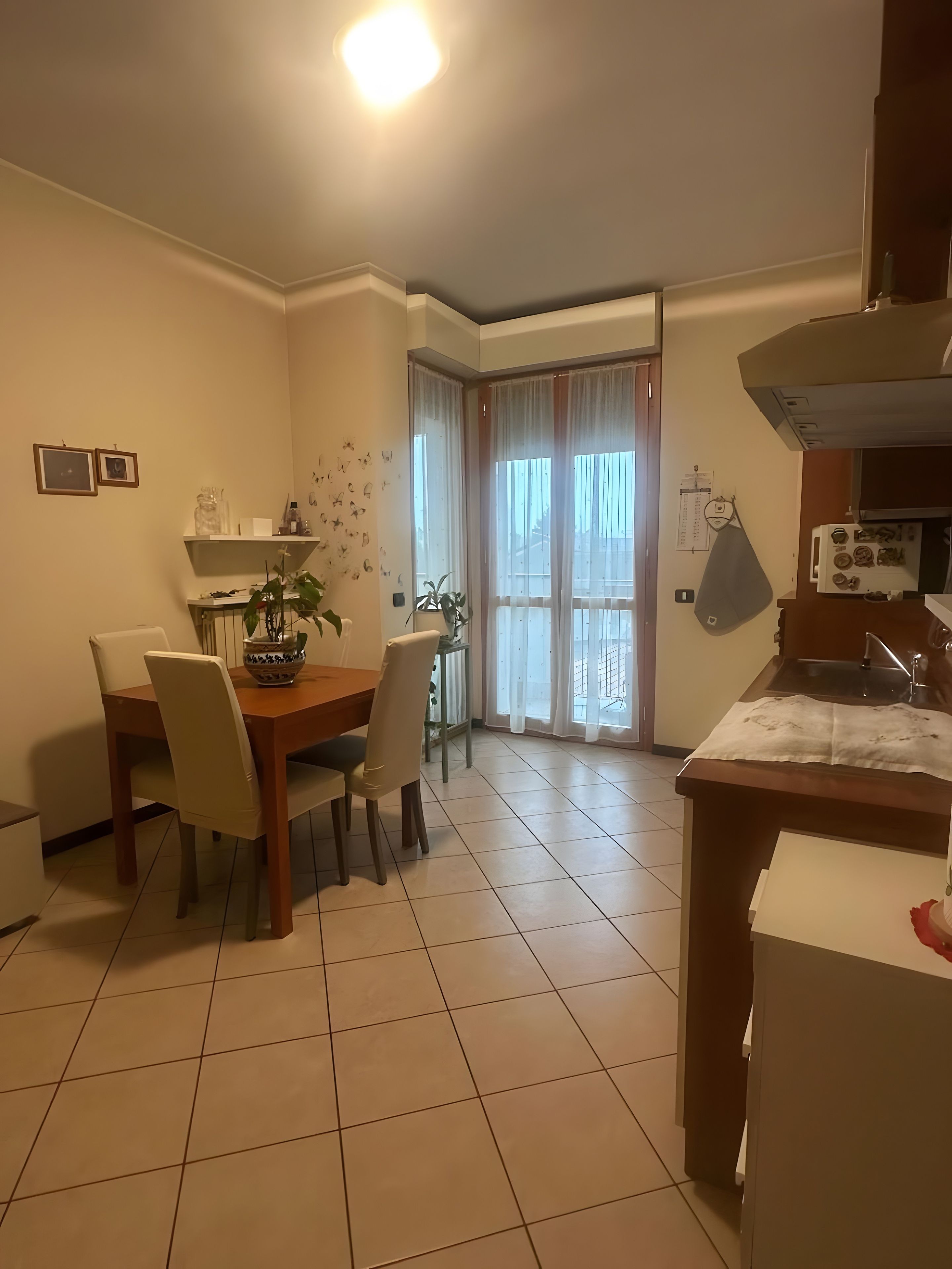 Un comedor con mesa y sillas, una cocina con estufa, y una ventana con cortinas.