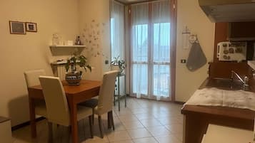 Un comedor con mesa y sillas, una cocina con estufa, y una ventana con cortinas.