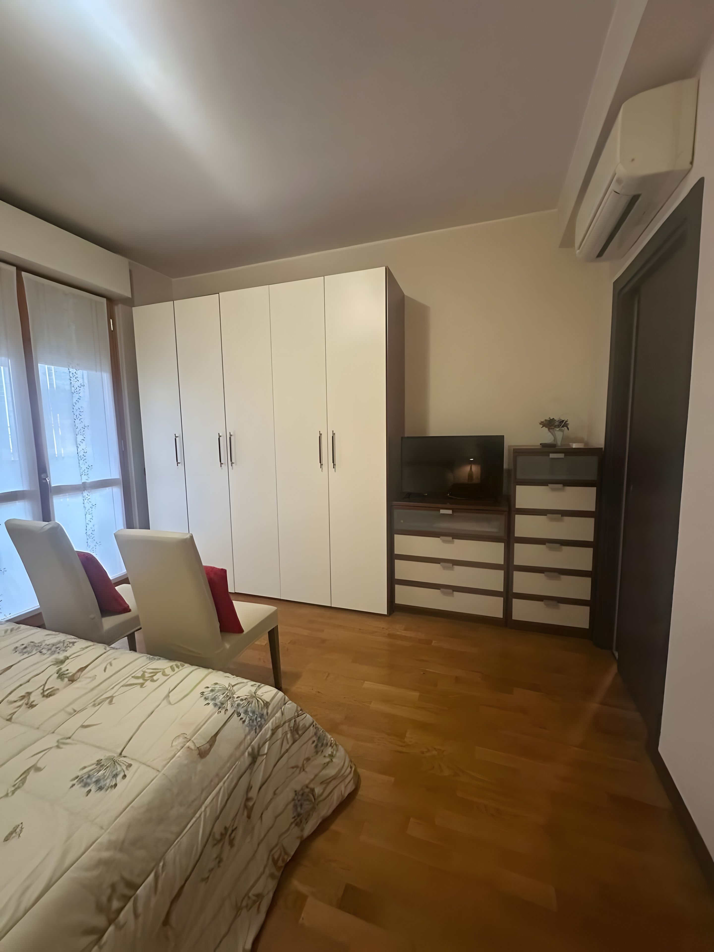 Une chambre à coucher avec un lit, une armoire, un bureau et un téléviseur.